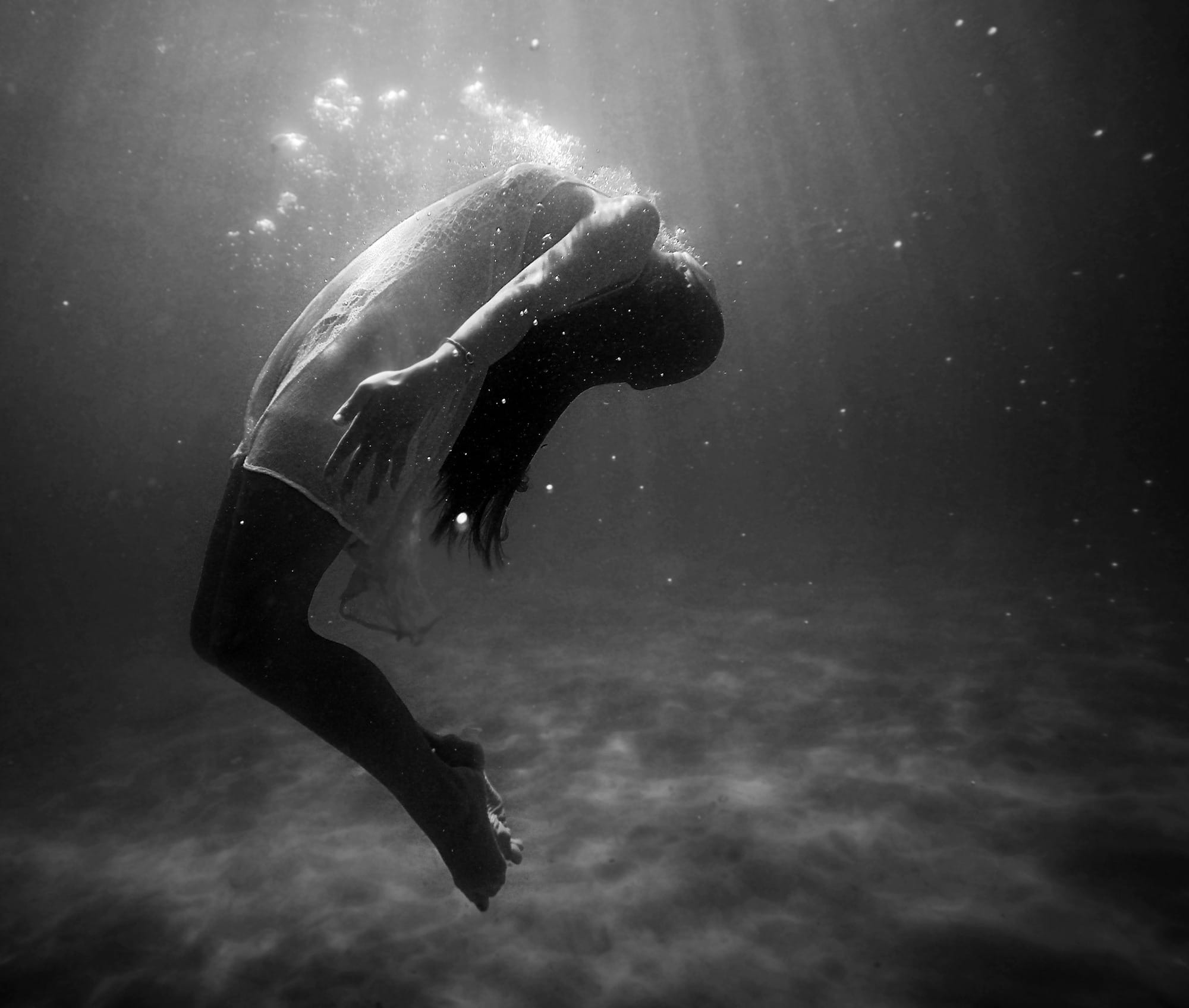 grayscale photo of woman drowning in water